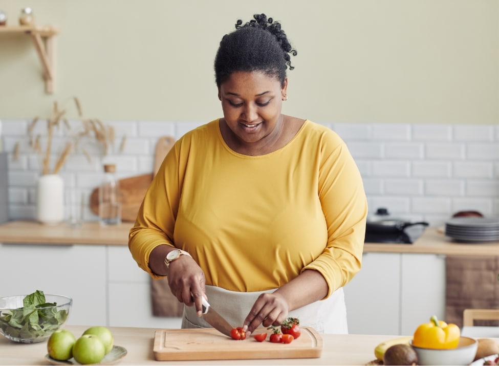 Black woman in kitchen chopping vegetables